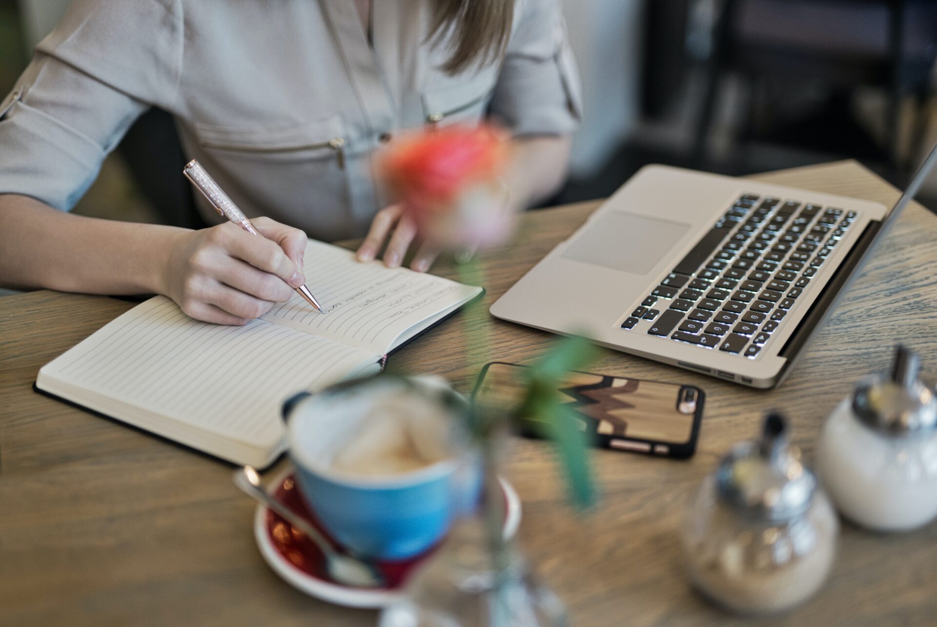 pexels-judit-peter-1766604 A women writing the content on notepad front of the laptop
